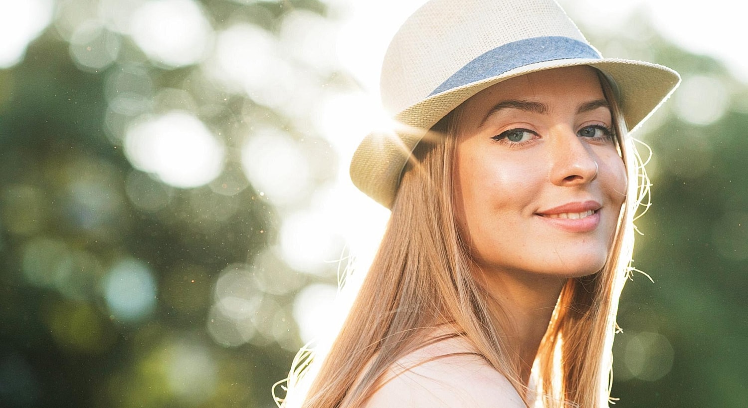 Smiling woman in a sunlit outdoor setting.
