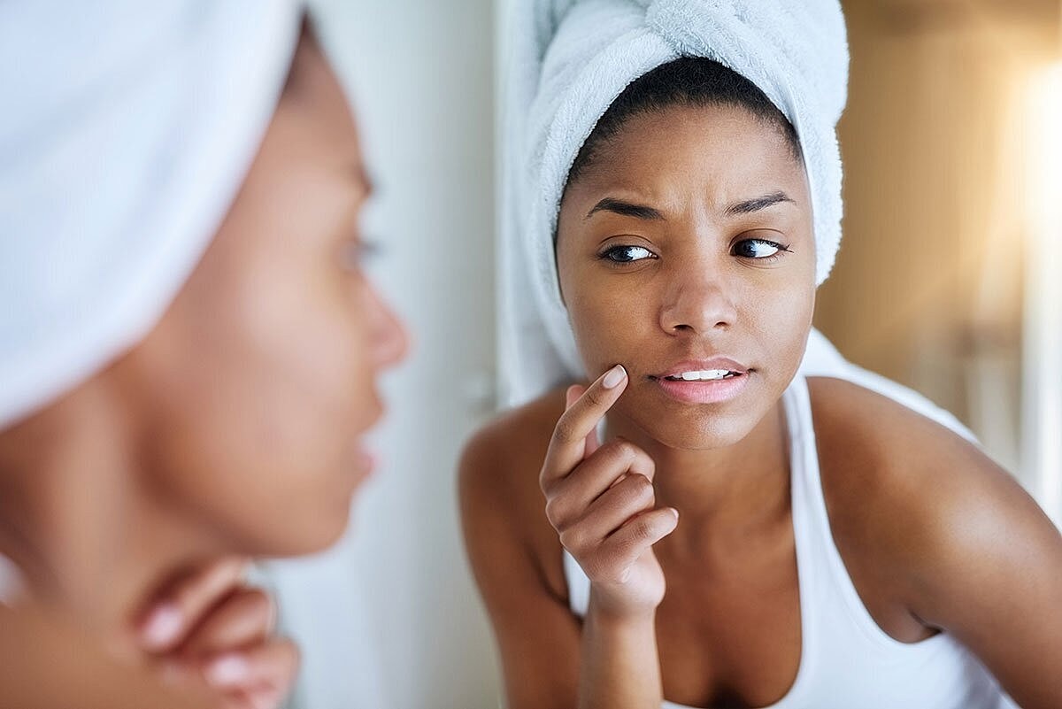 Woman examining her skin in the mirror.
