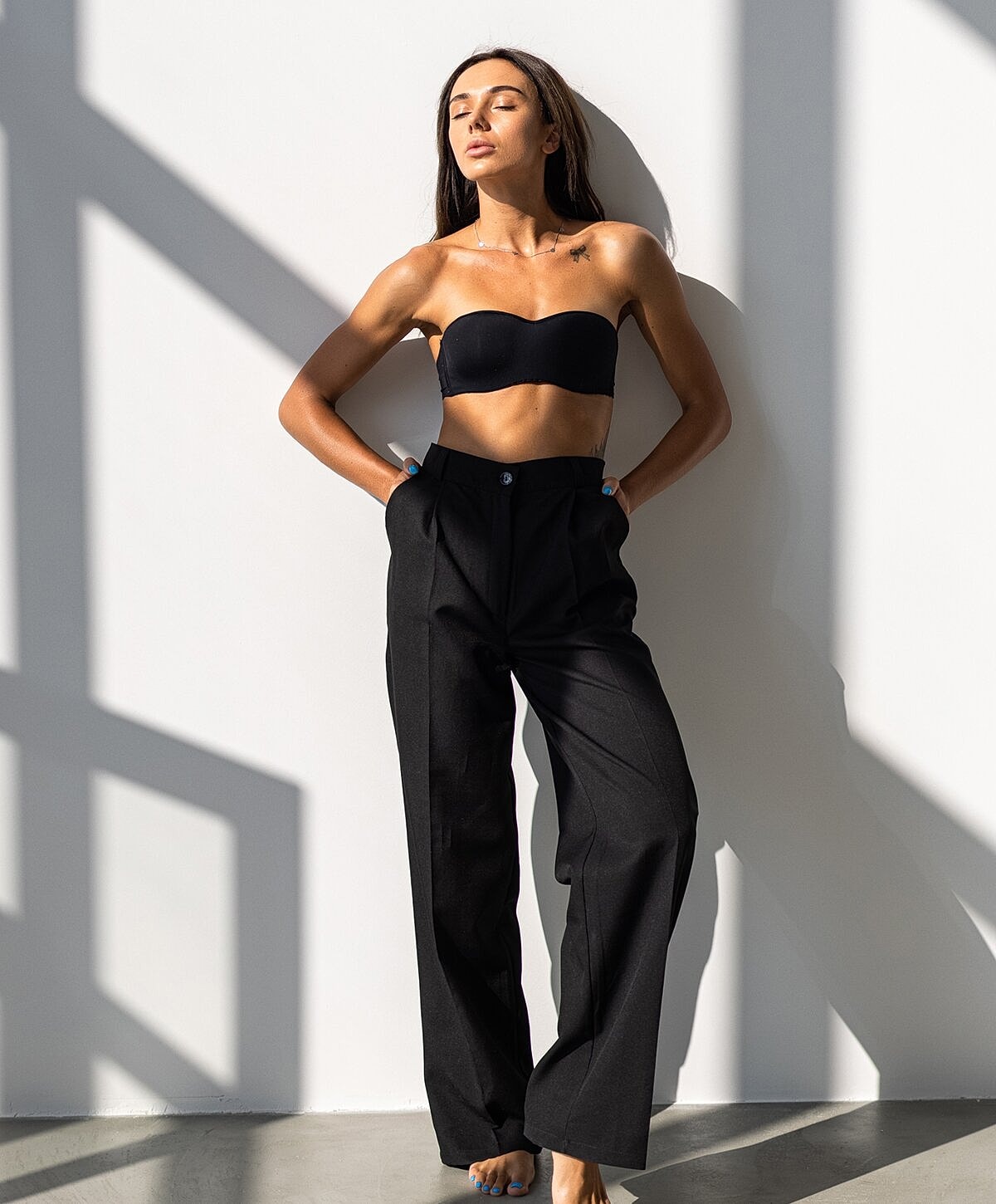 Denver Body Contouring model posing in stylish black outfit against wall.