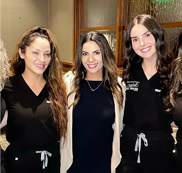 Three women in professional attire smiling together.