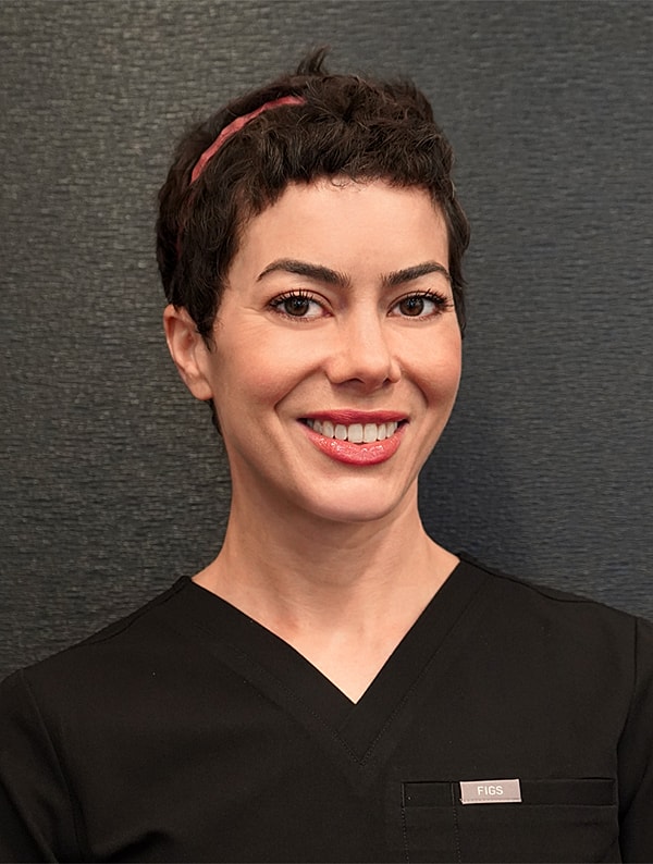 Smiling healthcare professional in dark scrubs.