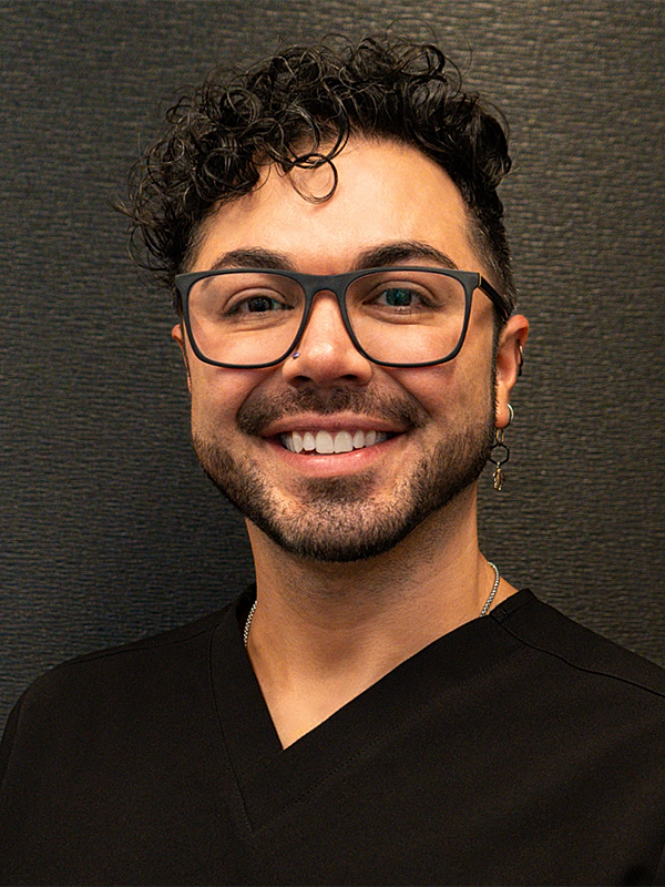 Smiling person wearing glasses and a dark shirt.