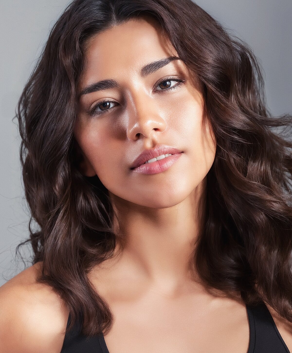 Mixed-race woman with wavy hair and smooth skin.