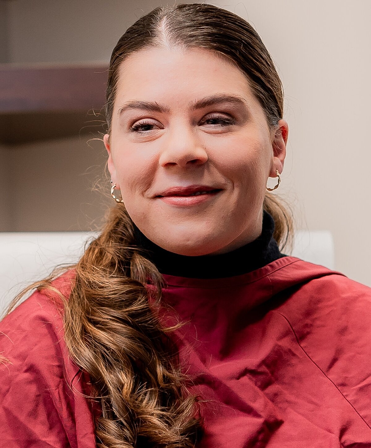 Smiling woman with long, wavy hair in salon.