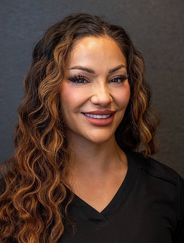 Smiling woman with curly hair in black top.