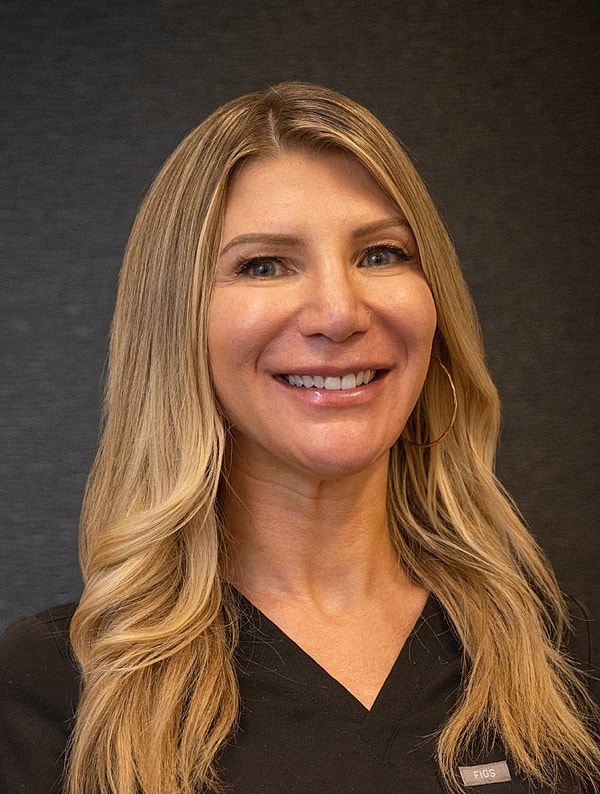 Smiling woman in medical scrubs with long hair.