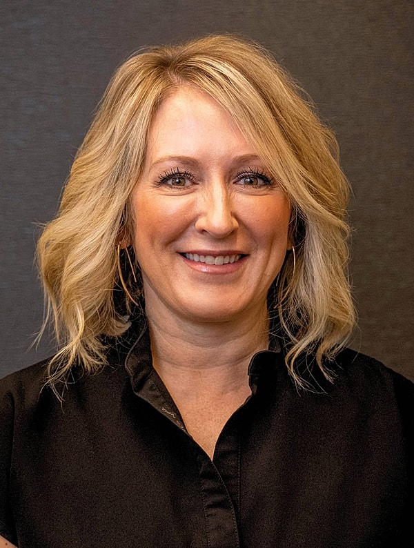 Smiling woman with blonde hair in black shirt.