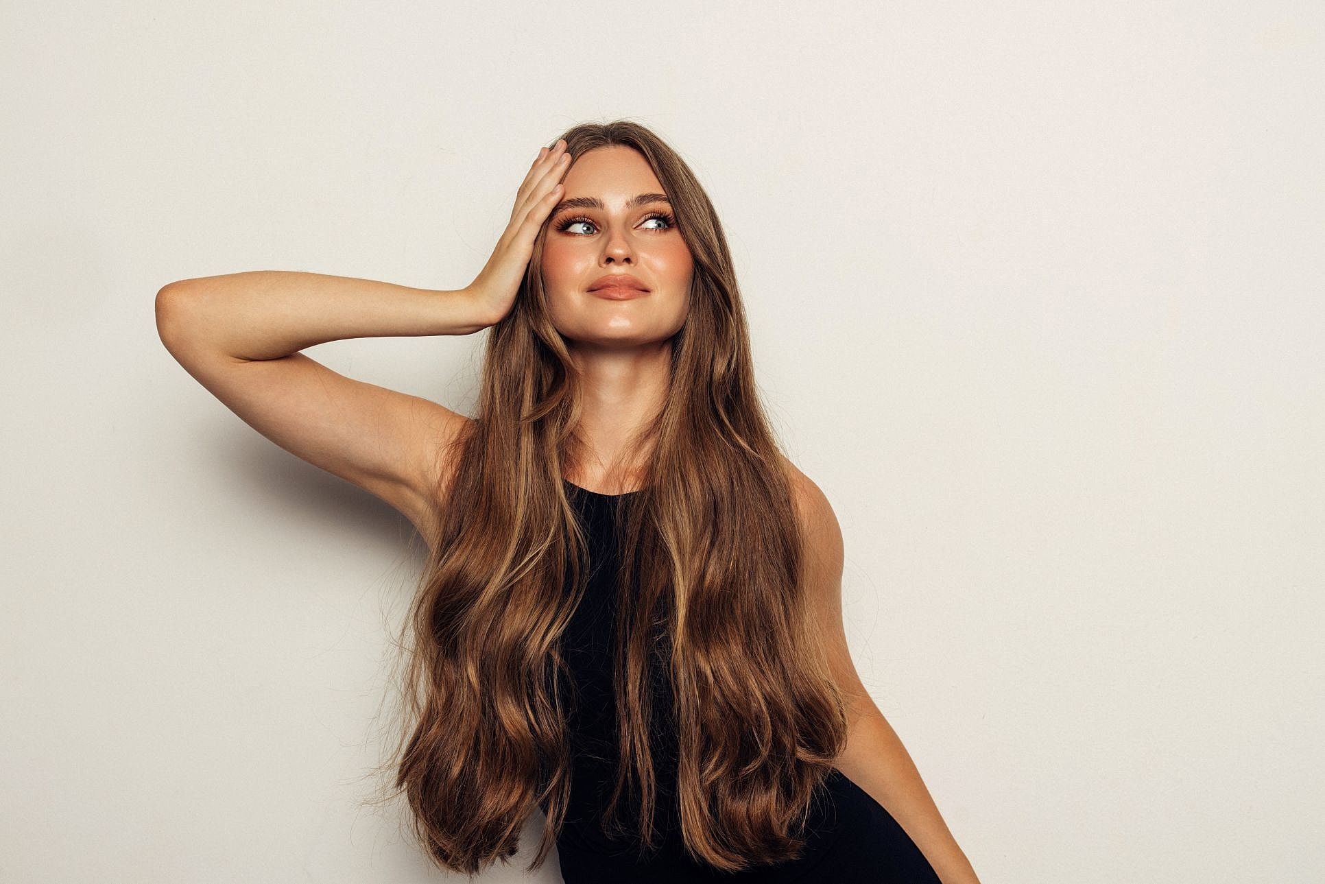 Woman with long brown hair and smooth, glowing skin.