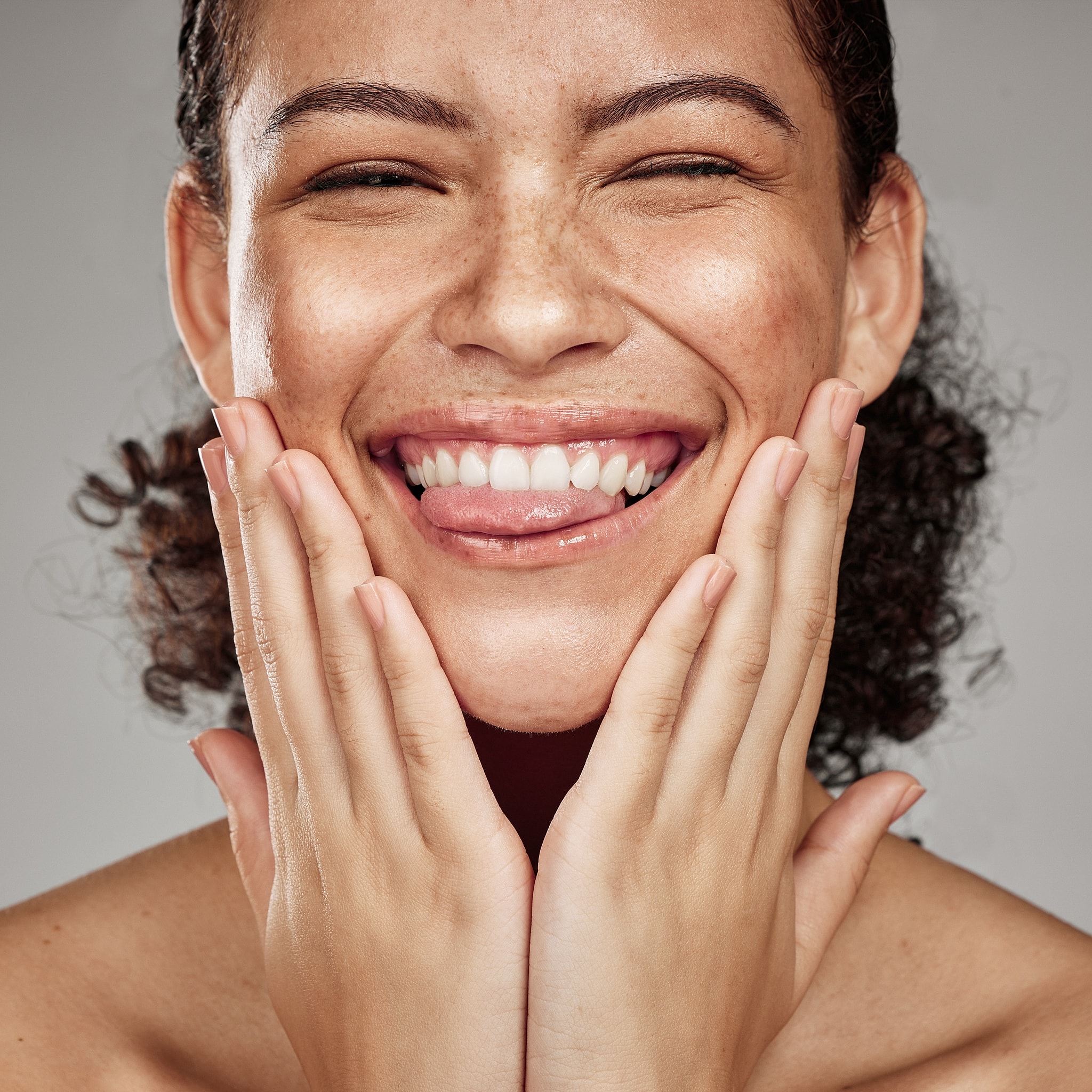 Smiling woman touching her face with hands.
