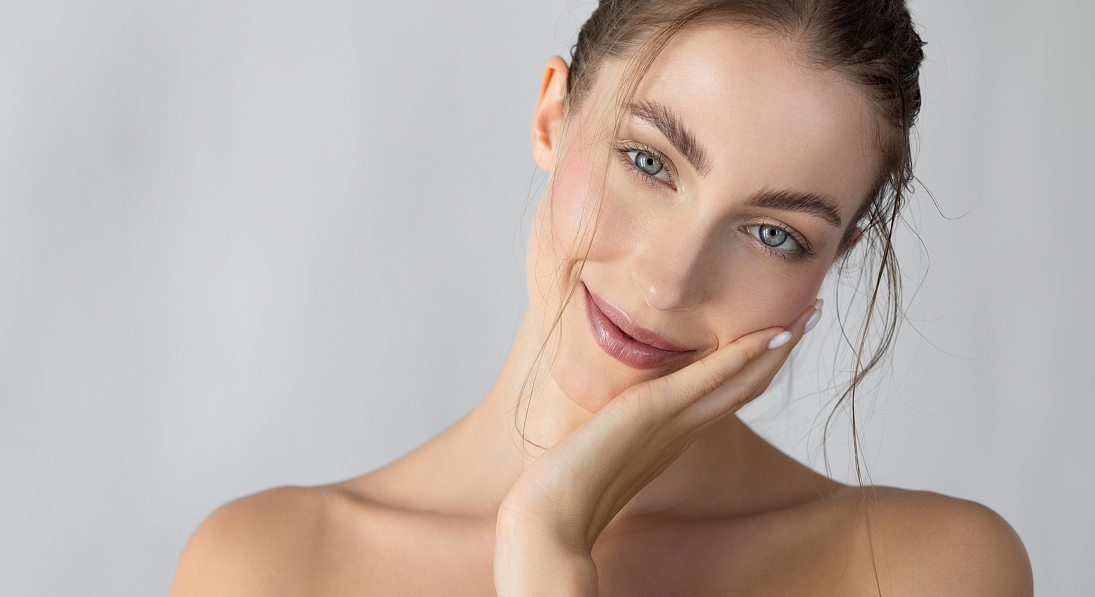 Smiling woman with natural makeup and soft background.